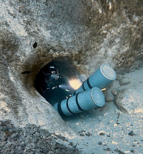 Scuba diver entering an underwater cave with bubbles